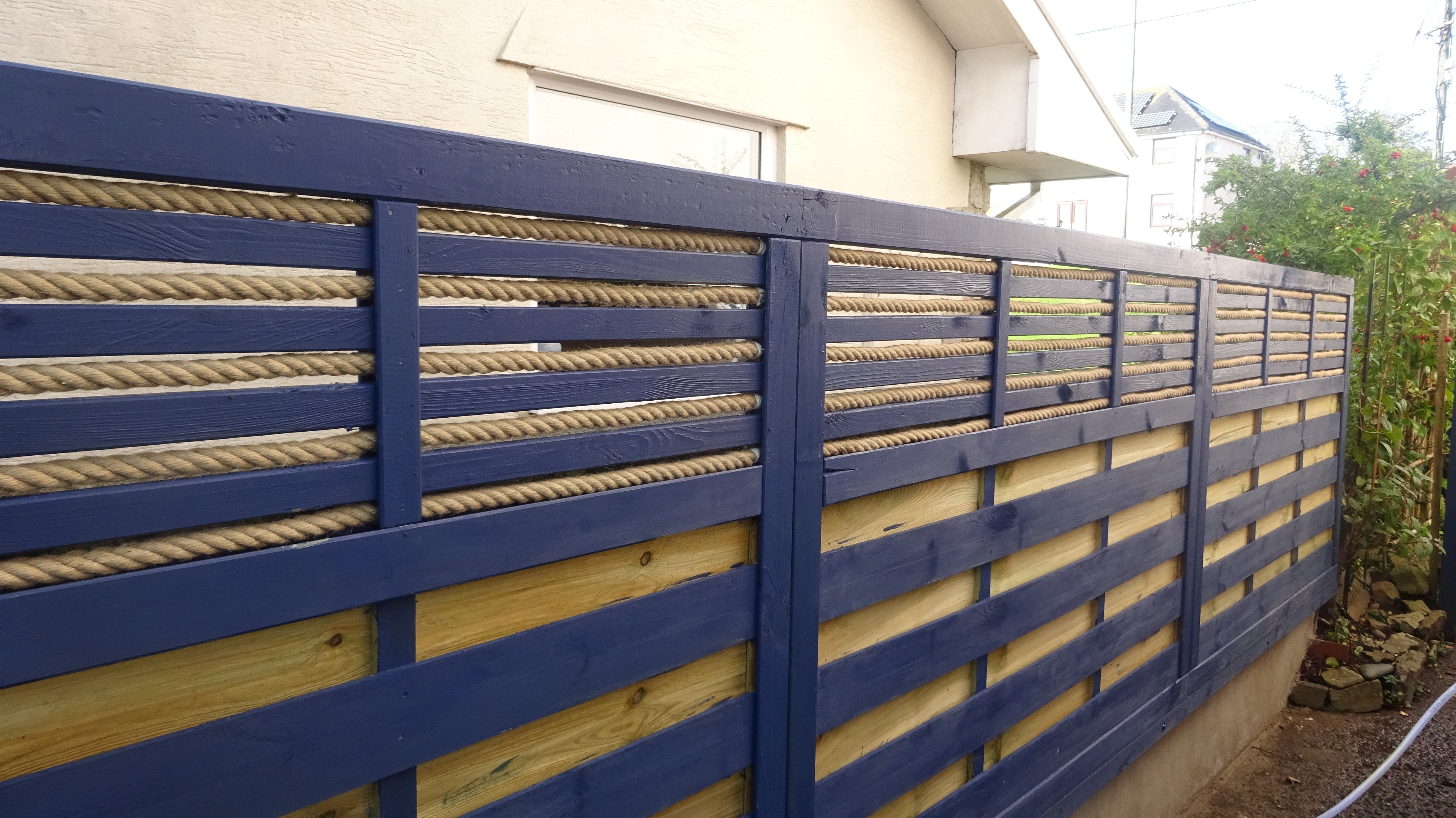Wooden fence with 20mm jute rope and blue horizontal slats in a residential area