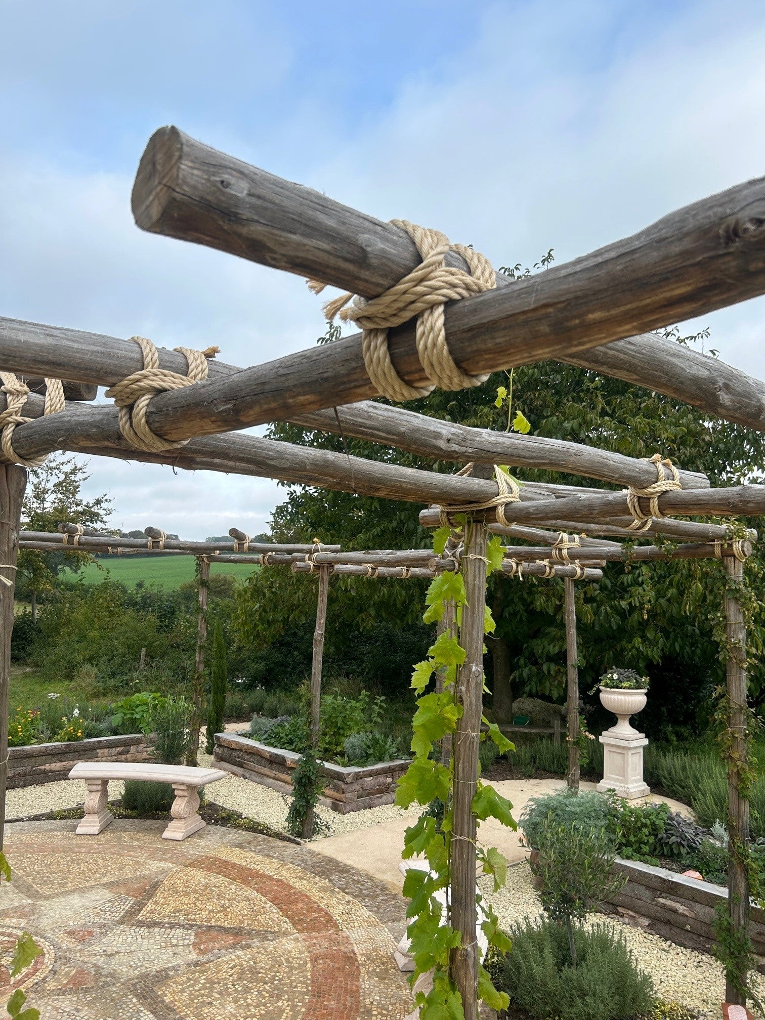 Wooden pergola using synthetic sisal rope with climbing plants in a garden setting